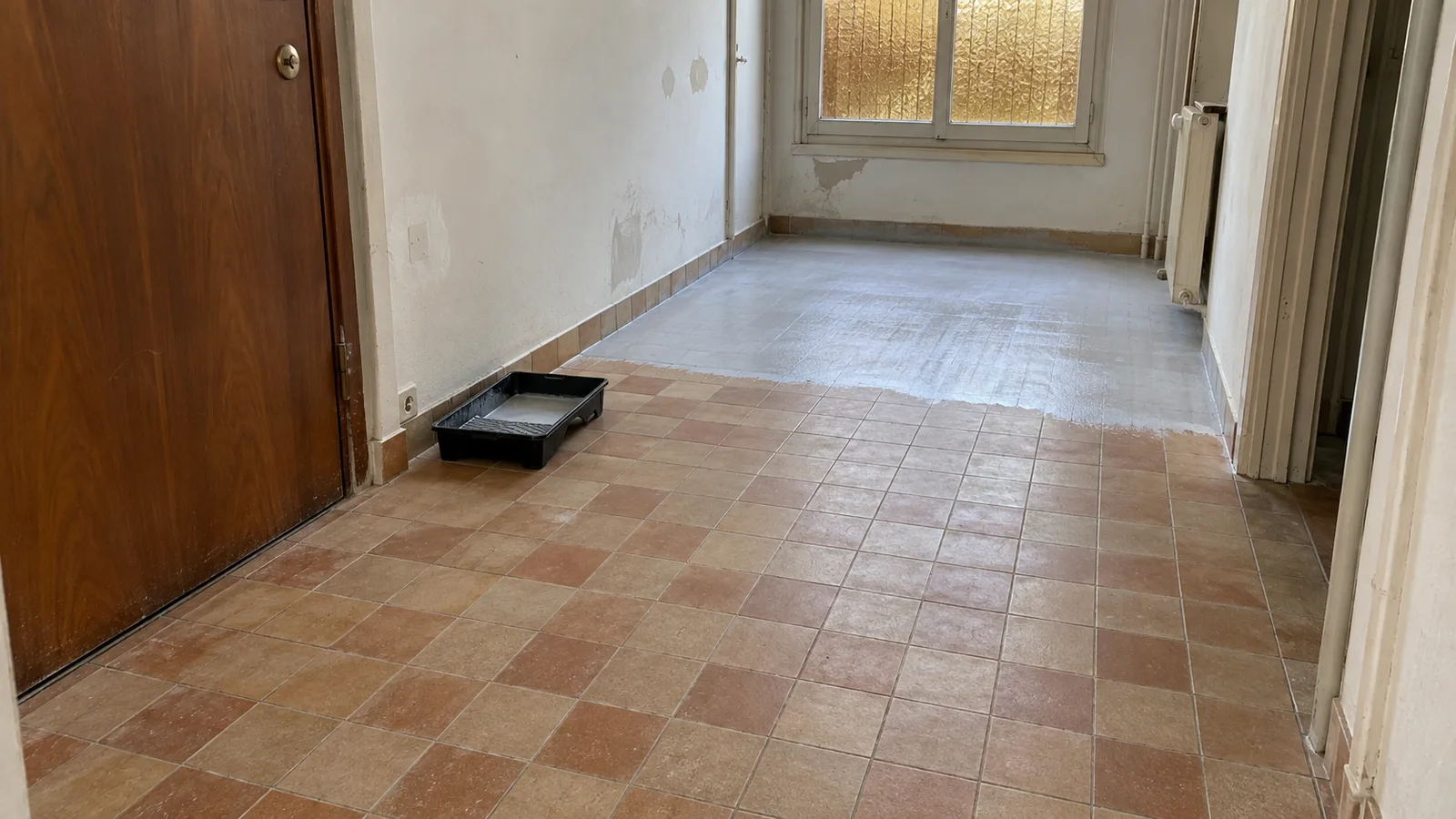 Ancien carrelage préparé dans un couloir d’appartement avant un ragréage