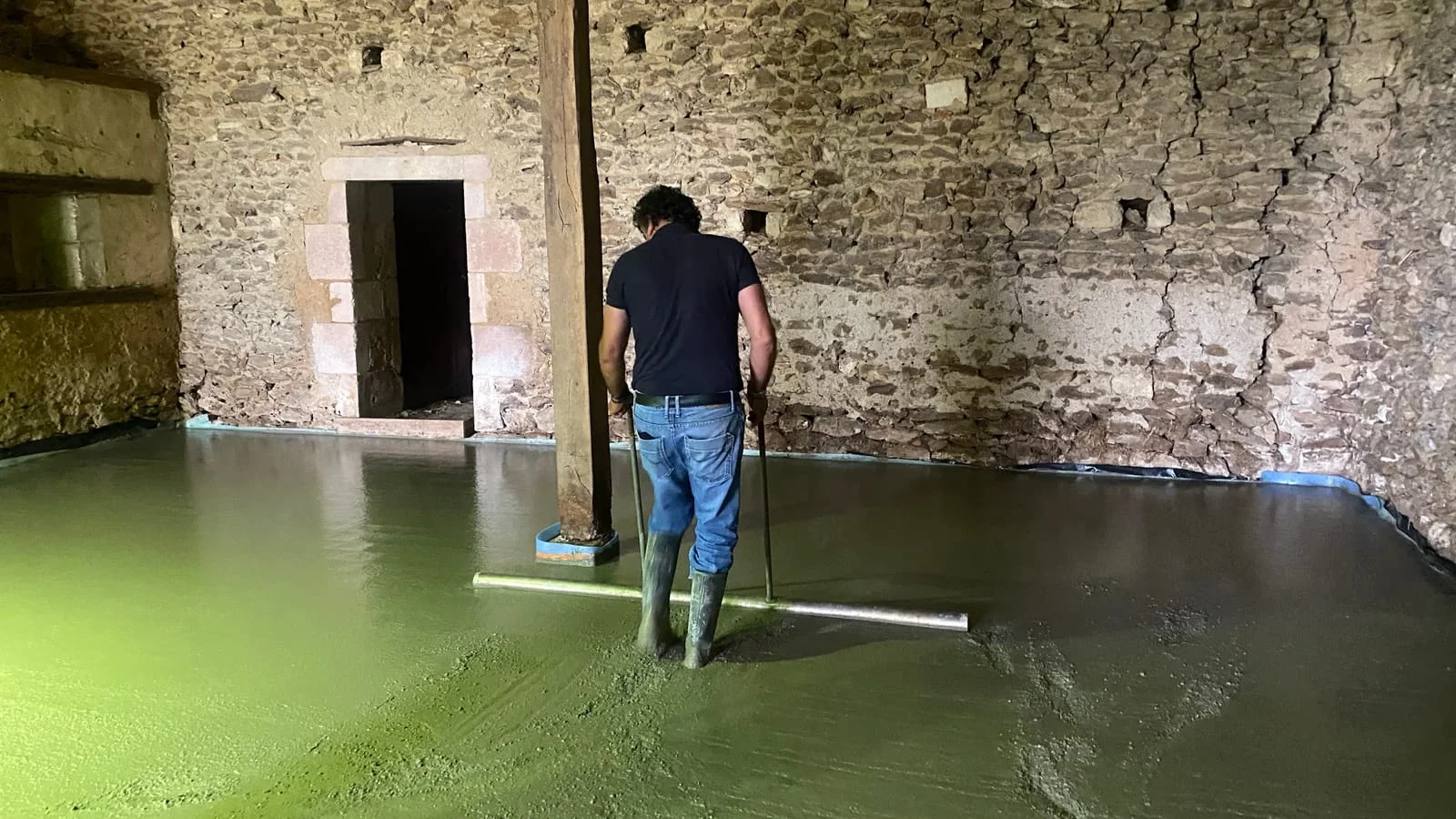 Professionnel mettant à niveau une chape liquide dans un bâtiment en rénovation